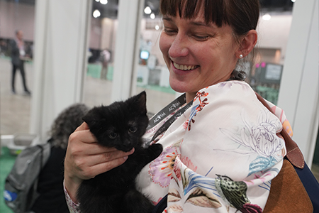 Woman smiling holding cat.