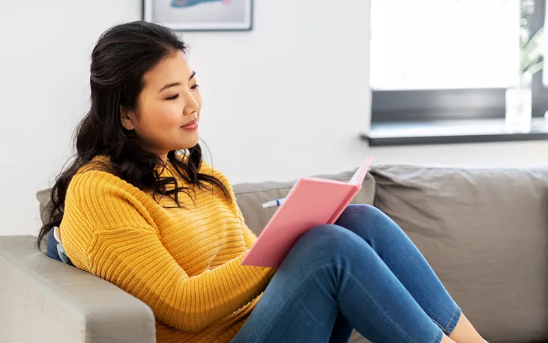Woman writing in a journal on a couch