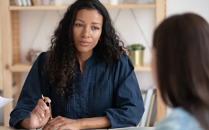 Woman holding a pen talking to another woman