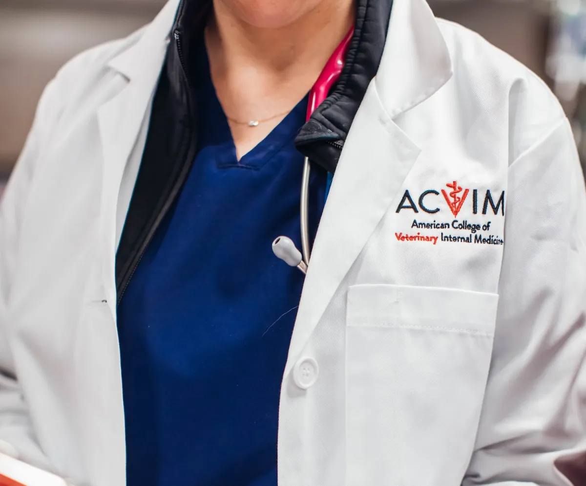 veterinarian wearing lab coat with ACVIM logo