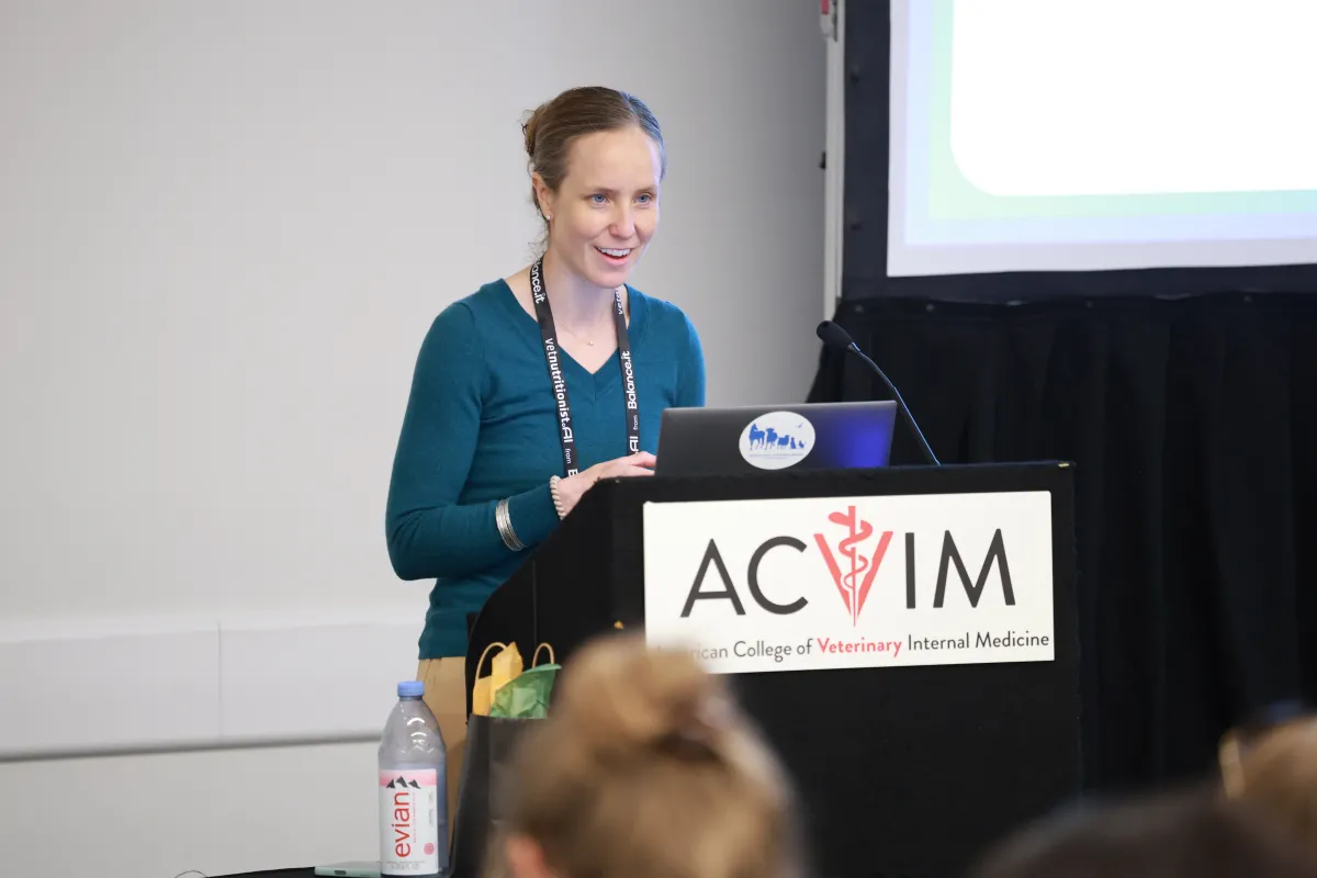 woman speaking at podium with ACVIM title