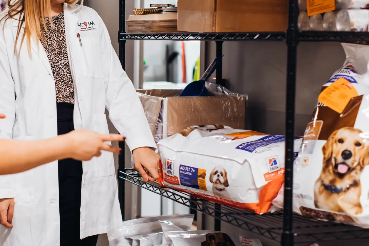 A veterinary specialist shows a client a shelf of specialized pet diet food options