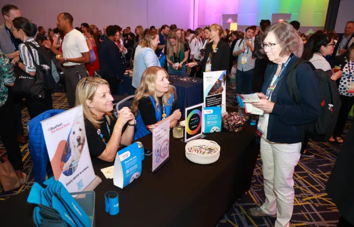 Attendee talking to sponsor at table in event room