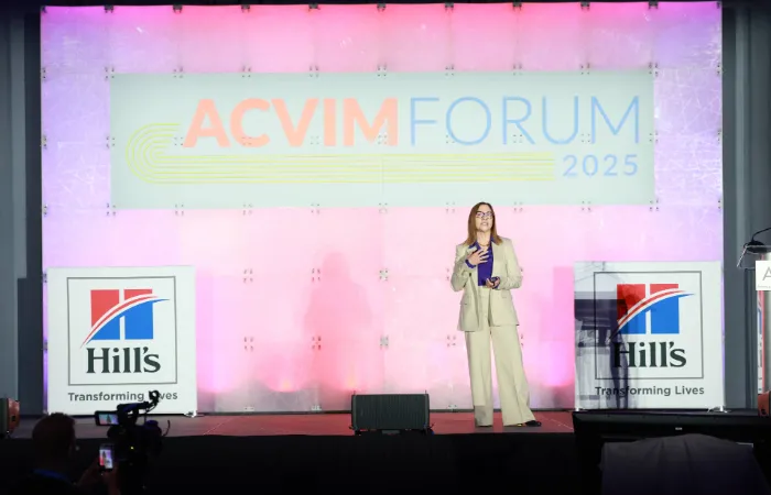 Keynote speaker on stage with sponsor logos on each side