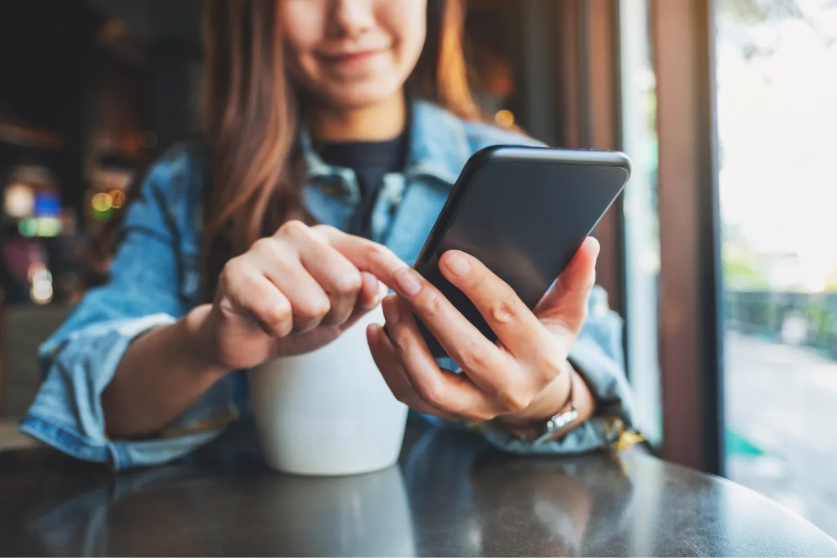 A woman checks her mobile phone while seated in a cafe