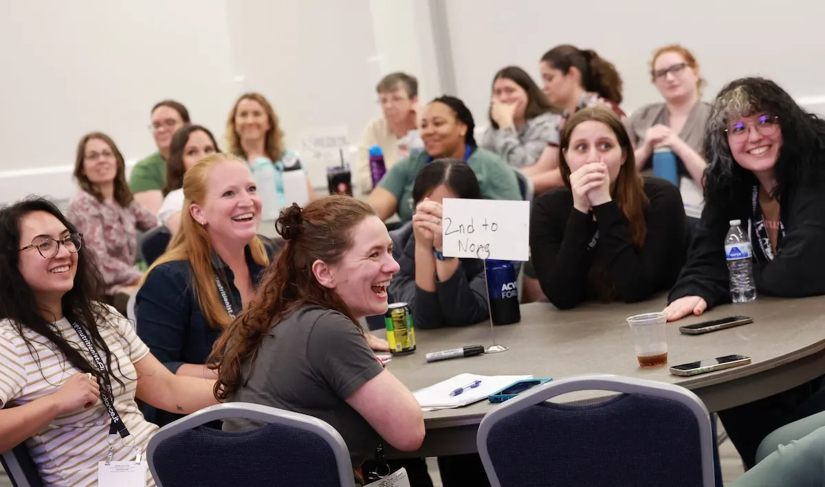 Attendees gathered around a table laughing playing a game