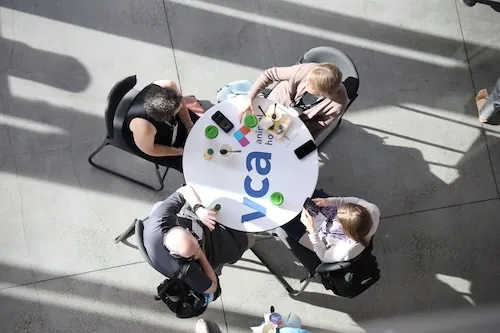 Top view of a table with a VCA logo and 4 attendees seated around it