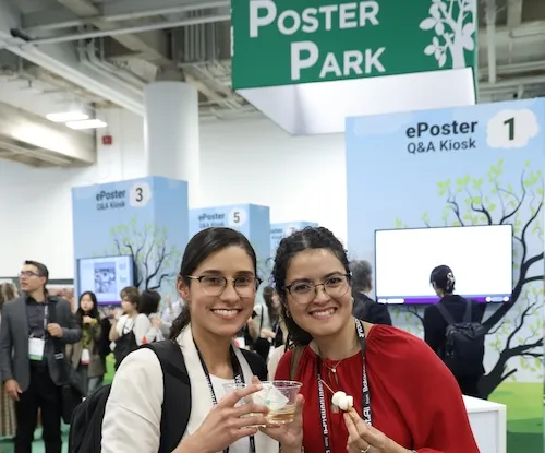 Two attendees in the poster park holding wine and cheese