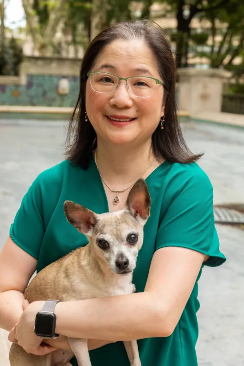 Dr. Jennifer Kim stands holding her pet Chihuahua mix.