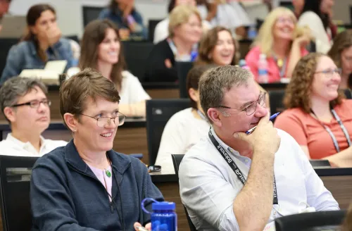 Attendees in session room laughing