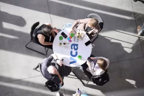 Top view of a table with a VCA logo and 4 attendees seated around it