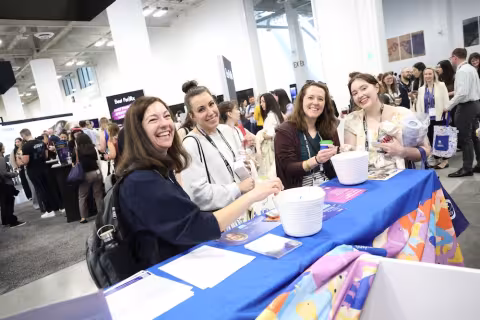 Attendees at booth in exhibit hall smiling